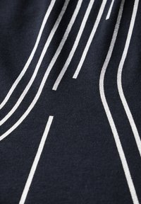 Námorníková látka s bílými svislými a diagonálními pruhy různých šířek. Hladký povrch se slabým leskem v zakřivených vzorech.