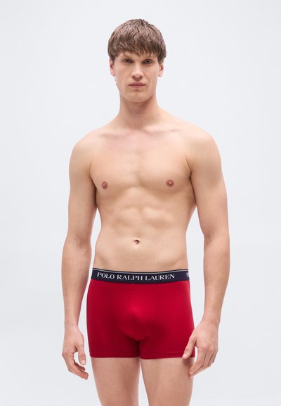Κόκκινα αντρικά εσώρουχα σλιπ από μαλακό ύφασμα, με σκουρόχρωμη μπλε ζώνη μέσης που φέρει το λογότυπο "POLO RALPH LAUREN". Σχεδιασμός εφαρμοστός με απαλό ύφασμα.