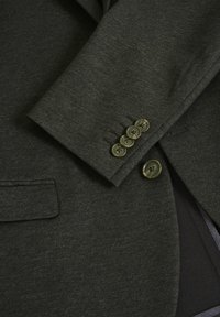 Dark green blazer featuring a textured fabric, four round buttons on the sleeve, and a subtle pocket detail on the front.