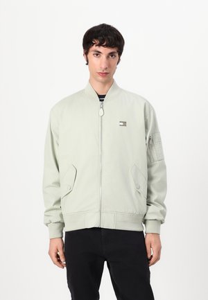 Giacca bomber verde chiaro con polsini a costine, chiusura con zip, tasche laterali e tasca con zip sulla manica sinistra. Tessuto dal tocco liscio e vestibilità casual.