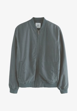 Vihreä pommisateen takki, jossa on vetoketjusuljenta, ribbireunat hihansuissa ja helmoissa, sivutaskut ja minimalistinen muotoilu. Valmistettu kevyestä kankaasta.