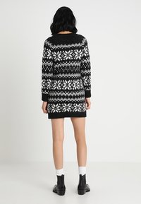 Abito in maglia bianco e nero con motivo a fiocco di neve, maniche lunghe, collo rotondo e polsini a costine, che termina sopra la metà della coscia.