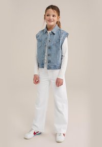 Denim veste ar gaiši zilu mazgājumu, ar smailu apkakli, pogu aizdari un divām krūšu kabatām. Apvienota ar baltām brīvām biksēm un kedām.