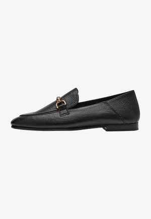 Mocassin en cuir noir texturé avec un ornement mors en or sur le devant et un petit talon plat.