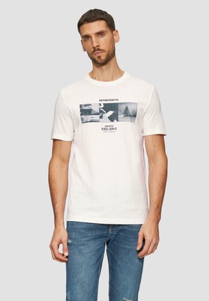 Witte katoenen T-shirt met een grafische print van zwart-wit beelden, tekst en een ronde hals. Draagt met blauwe, versleten jeans.