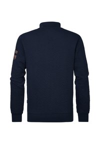 Mörkblå texturerad tröja med hög krage, utrustad med ett zigzag-mönster och en patch på vänster ärm. Ribbad mudd och nederkant.