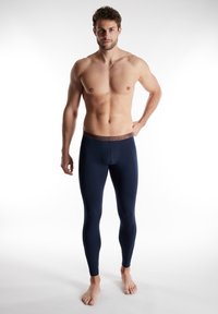 Navyfarbene Leggings mit eng anliegender Passform und elastischem braunem Bund. Der Stoff wirkt glatt und dehnbar, geeignet für aktive oder lässige Trageanlässe.