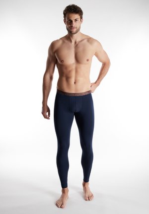 Navyfarbene Leggings mit eng anliegender Passform und elastischem braunem Bund. Der Stoff wirkt glatt und dehnbar, geeignet für aktive oder lässige Trageanlässe.