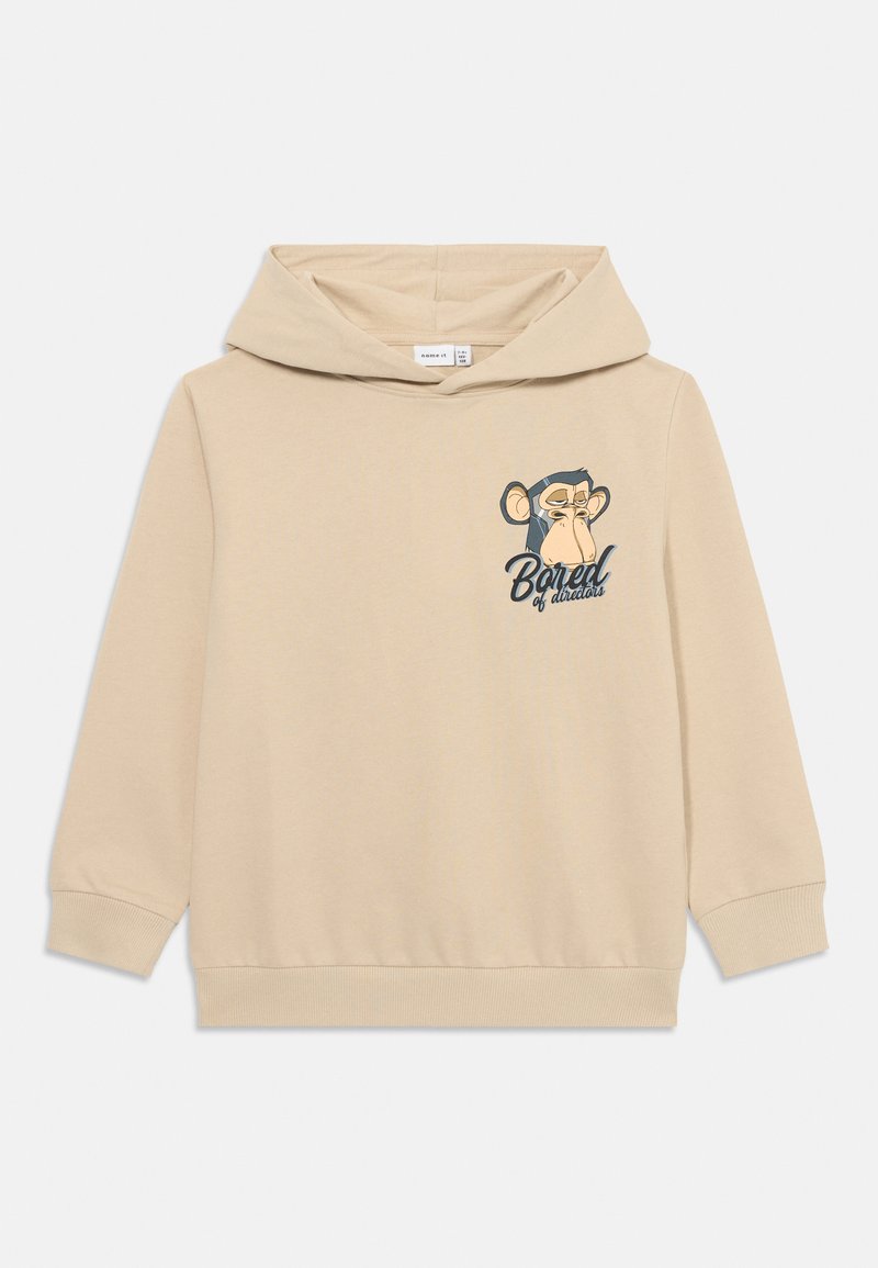 Sudadera con capucha beige hecha de un tejido suave, con un gráfico de un mono en el lado izquierdo del pecho y el texto "Bored of دنیا" debajo.