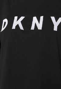 Musta puuvillapaita, jossa on suuri valkoinen brodeerattu "DKNY"-logo edessä. Materiaali on sileä ja hieman kiiltävä.