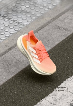 Lightweight athletic shoe in coral and white; features a breathable mesh upper, a padded collar, and a textured rubber sole.
