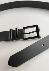 Sort læderbælte med en rektangulær metalspænde, teksturerede detaljer og en glat overflade. Justerbart med flere huller til tilpasning af størrelse.