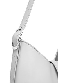 Šedý kožený popruh na rameno s stříbrným kováním, vybavený smyčkou a hladkým povrchem, který zdůrazňuje minimalistické designové prvky.