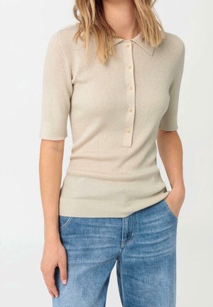 Lichtbeige geribd gebreid poloshirt met korte mouwen en een knoopsluiting aan de voorkant. Voorzien van kleine beige knopen en een getailleerd silhouet.