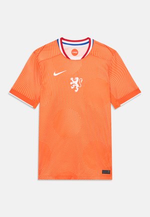 Maglia Nike arancione con emblema di leone, motivo a pois, colletto a contrasto rosso e blu, maniche corte e tessuto testurizzato.