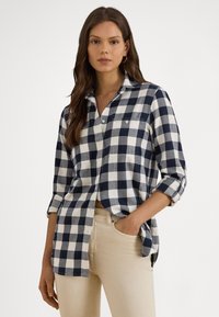 Tmavomodrá a biela kockovaná košeľa s golierom, zapínaním na gombíky, vyhrnutými rukávmi, vyrobená z mäkkej látky, s náprsným vreckom.