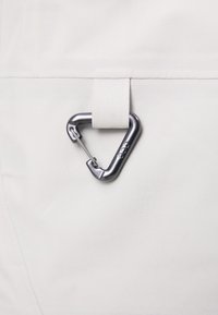 Vit tyg med en triangulär silverkarbinhake fäst vid en tygslinga, som betonar en elegant design och funktionell hårdvarudetalj.