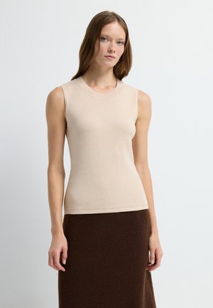 Beige mouwloos topje met een ronde halslijn, gemaakt van zachte stof, gecombineerd met een bruin gestructureerd wollen rok. Eenvoudig en aansluitend ontwerp.