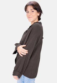 Black textured button-up shirt with long sleeves and a relaxed fit, paired with light blue jeans. The shirt features a subtle grid pattern.