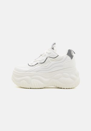 Białe sneakersy na platformie z falistą grubą podeszwą, siateczkową i skórzaną cholewką, zapięciem na sznurówki oraz odblaskowymi detalami na pięcie i języku.