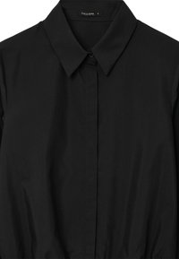 Camicia nera con bottoni, caratterizzata da un colletto classico, una texture liscia e un design minimalista con una leggera lucentezza. L'etichetta riporta "CALLIOPE" taglia S.
