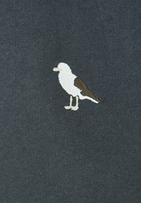 Tessuto di maglia grigio scuro con un piccolo uccello ricamato in bianco e marrone, posizionato nella parte superiore sinistra.