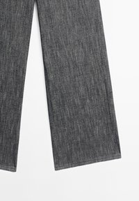 Pantalon en denim gris foncé à coupe droite posé à plat sur un fond blanc, montrant la texture du tissu et les détails de couture.