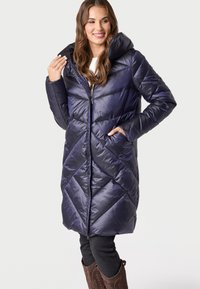 Marineblauwe gewatteerde jas met een chevronpatroon, voorzien van een capuchon, ritssluiting aan de voorkant en zijzakken. Glanzend, geïsoleerd materiaal voor warmte.