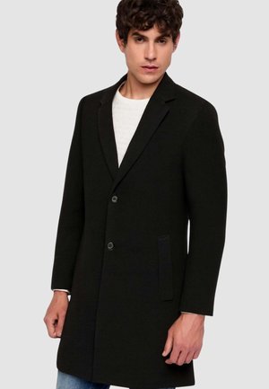 Cappotto nero in lana con vestibilità sartoriale, design monopetto, rever a lancia, due tasche frontali e chiusura con bottoni. Maniche lunghe, trama minimale.