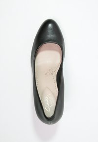 Escarpin en cuir noir avec un bout arrondi, texture lisse et semelle intérieure rembourrée, ornée de surpiqûres légères et d'un logo de marque.