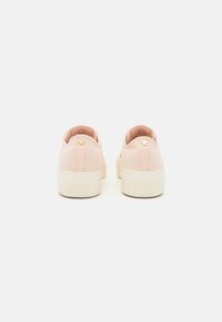 Rózsaszín vászon slip-on cipők fehér gumitalppal, hátul kis arany csillag díszítéssel és textúrált szövet részletekkel.