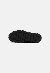 Suela de zapato de goma negra con patrón texturizado, que presenta surcos profundos y un ribete distintivo a lo largo de los bordes para una mayor tracción y durabilidad.