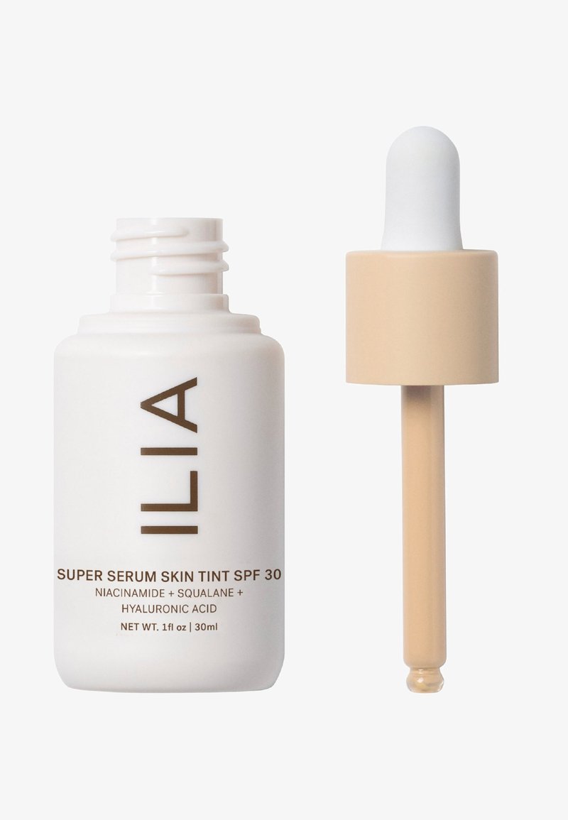 Flacon de ILIA Super Serum Skin Tint SPF 30 en blanc avec lettering marron. Présente un capuchon beige et un applicateur compte-gouttes. Taille de 30 ml.