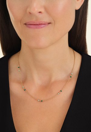Gouden ketting met kleine groene, witte en bruine kralen, met een delicaat ontwerp dat comfortabel om de hals rust.