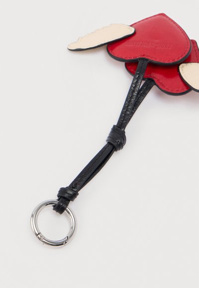 Δερμάτινο μπρελόκ με κόκκινες και μπεζ καρδιές προσαρτημένο σε ασημένιο μεταλλικό δακτύλιο πάνω σε λευκό φόντο.