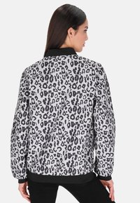 Bunda bomber s leopardím potiskem, černým ribbed límcem a manžetami. Vyrobena z lehkého materiálu, s bílým a černým vzorem.