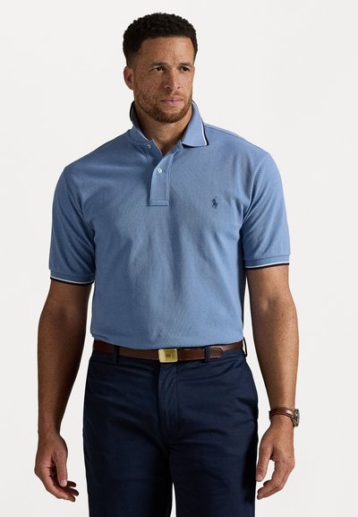Camisa polo de color azul claro y manga corta con un patrón texturizado, que presenta un collar con una franja de contraste y un pequeño logo en el pecho.