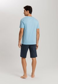 Light blue short-sleeve t-shirt; navy shorts with white floral pattern; relaxed fit; visible stitching; plain design without hardware.