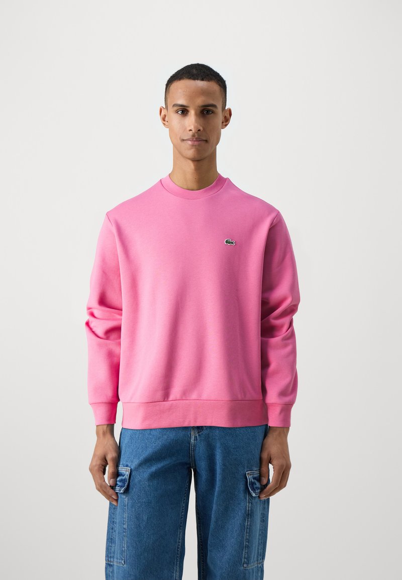 Felpa rosa realizzata in tessuto misto cotone con collo a giro e polsini a coste. Presenta un piccolo logo verde ricamato sul petto.