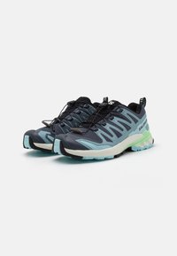 Lightweight running shoes featuring a black and teal mesh upper, cushioned white midsole, and green accents on the outsole and heel.