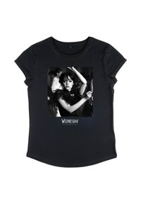 Black T-shirt featuring a black-and-white photo of a woman dancing with arms raised, labeled "Wednesday" below the image.