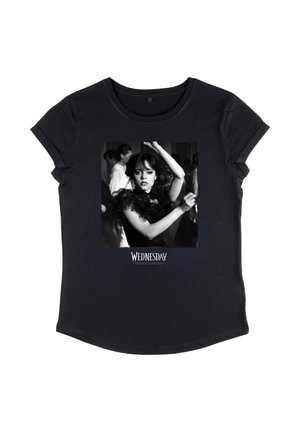 T-shirt nera con una foto in bianco e nero di una donna che danza con le braccia alzate, con la scritta "Mercoledì" sotto l'immagine.