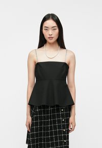 Czarny top peplum z regulowanymi, błyszczącymi ramiączkami, textured materiałem i dopasowanym korpusem. Połączony z czarną, w kratkę spódnicą.