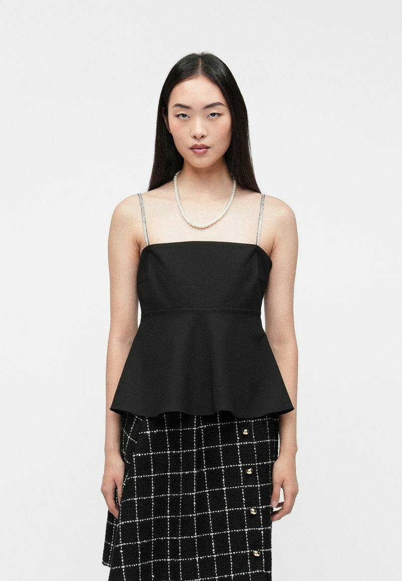 Czarny top peplum z regulowanymi, błyszczącymi ramiączkami, textured materiałem i dopasowanym korpusem. Połączony z czarną, w kratkę spódnicą.