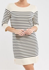 Randig klänning i kräm och marinblå, med trekvartslånga ärmar, rund halsringning och sprund i nederkant. Mjuk, elastisk tyg.