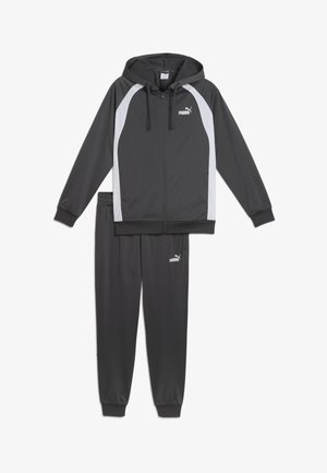 Tuta grigia composta da una felpa con zip con accenti bianchi e pantaloni coordinati. Realizzata in materiale sintetico liscio con polsini elastici.
