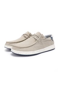 Beige canvas shoes with a rounded toe, textured fabric, and a speckled white sole. Blue patterned lining visible inside. Laces included.