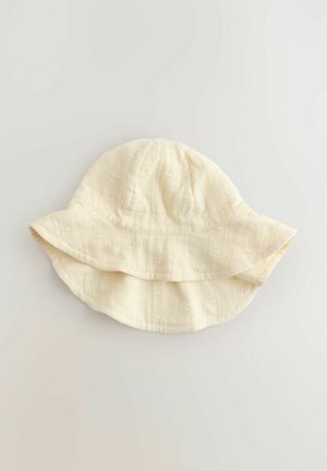 Bawełniany kapelusz typu bucket w jasnokremowym kolorze z teksturowanym wzorem kropek, z szerokim, miękkim rondem i luźnym, swobodnym kształtem.