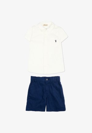 Chemise blanche à manches courtes avec boutons et petit logo noir sur la poche, associée à un short bleu marine à taille élastique.