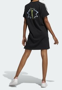 Abito t-shirt nero in cotone con maniche corte, scollatura rotonda e una grafica sul retro. Accenti includono strisce bianche sulle maniche.